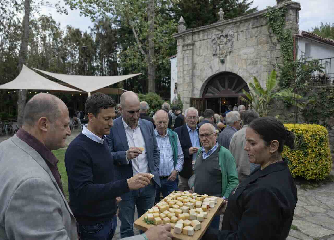 Asistentes al II Congreso del Queso de Cantabria degustando trozos de queso en el jardín de El Nuevo Molino, en Puente Arce