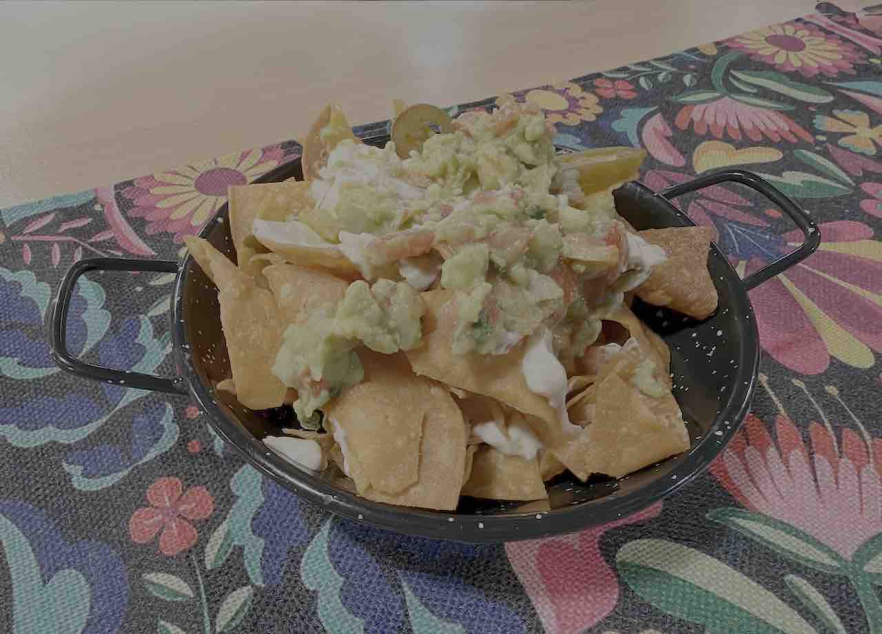 Nachos clásicos con queso cheddar, guacamole y jalapeños