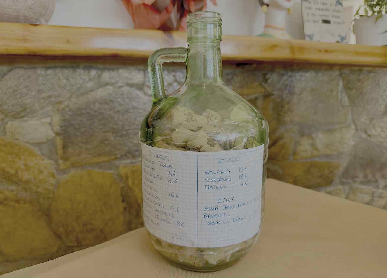 Carta de vinos manuscrita sobre una garrafa de cristal en Lenteja, Castro Urdiales